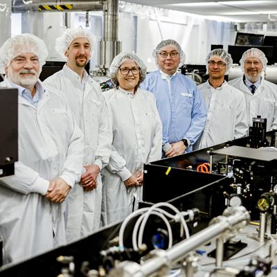 The collaborators on a project along side Donna Strickland stand by the laser