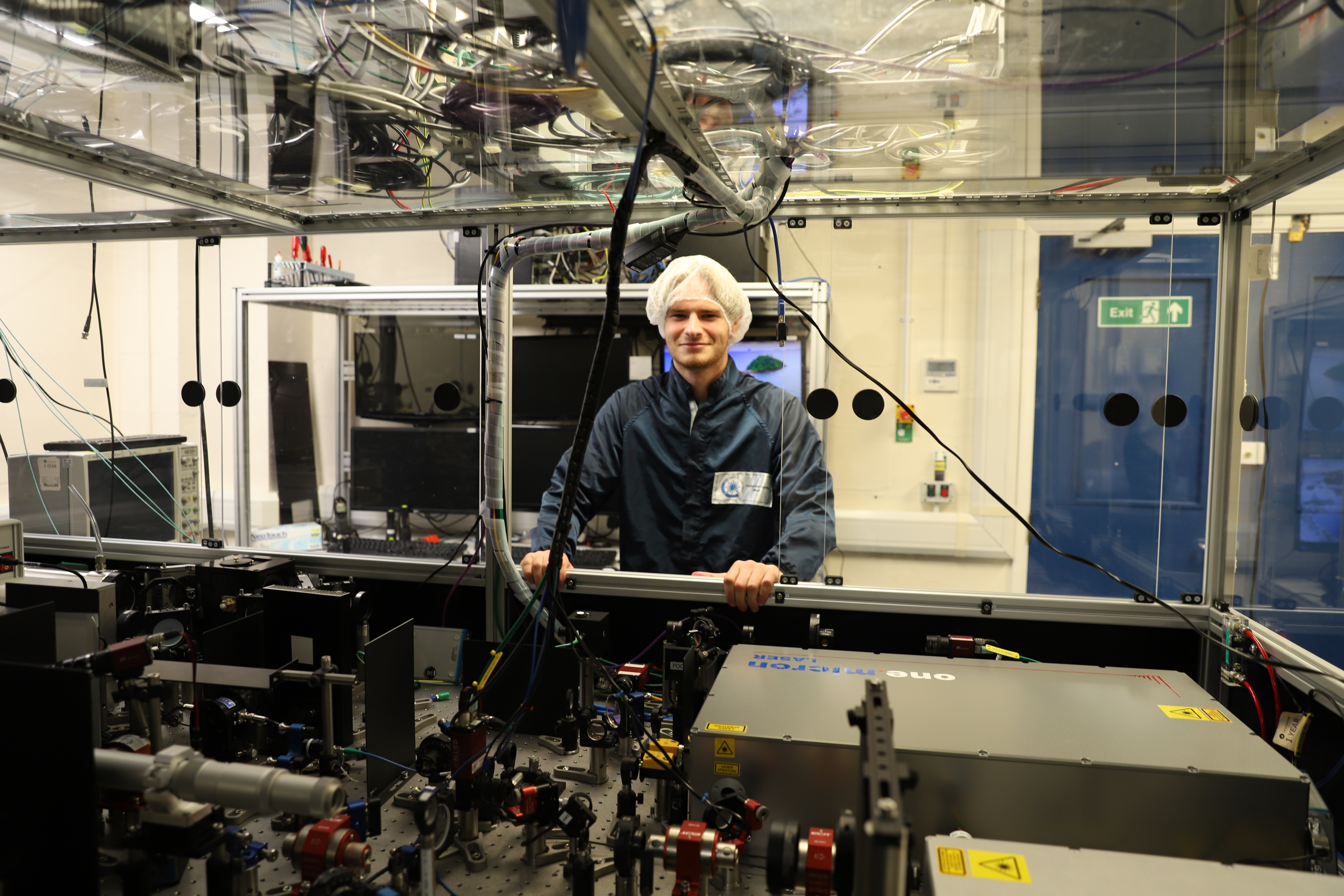 Aleksander in the CALTA labs standing with optics for DiPOLE