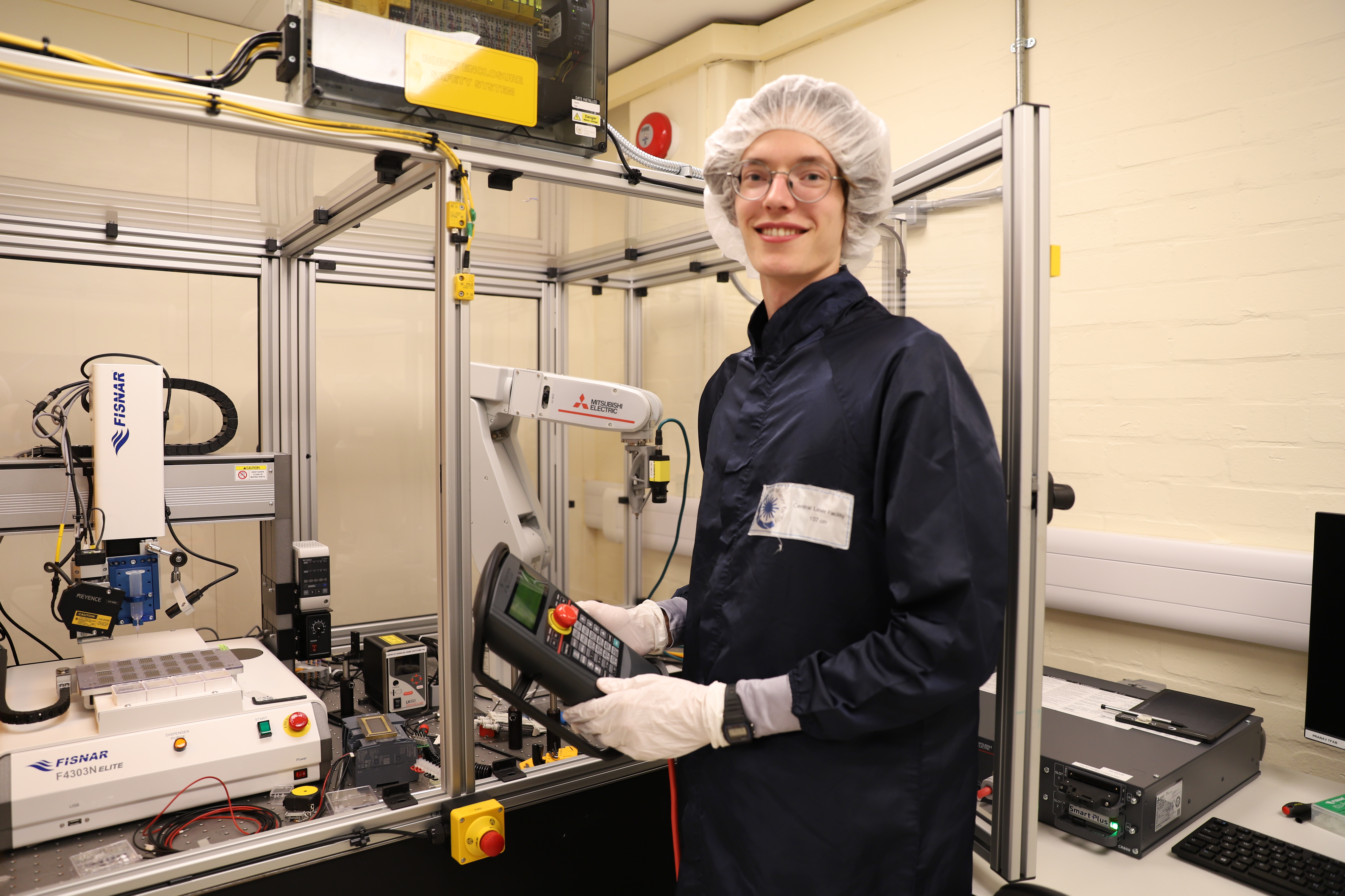 Christopher in cleanroom kit with the robotic equipment for his project