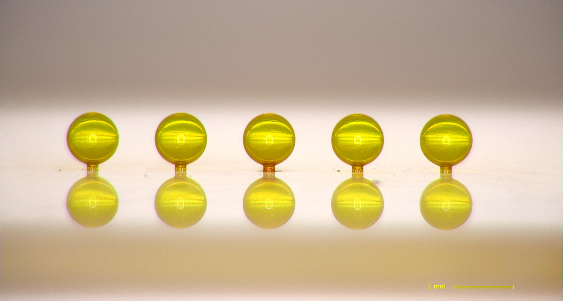 Line of gold spherical capsule targets each less than 1mm diametre