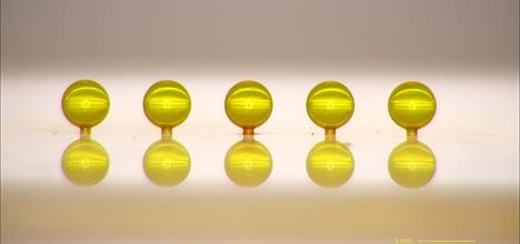 Line of gold spherical capsule targets each less than 1mm diametre
