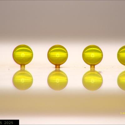 Line of gold spherical capsule targets each less than 1mm diametre