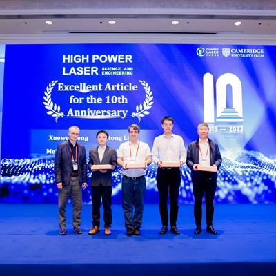 5 people stand on a stage decorated with blue HPLSE signage stage. 4 of the 5 are holding trophies. Pedro is in the middle.