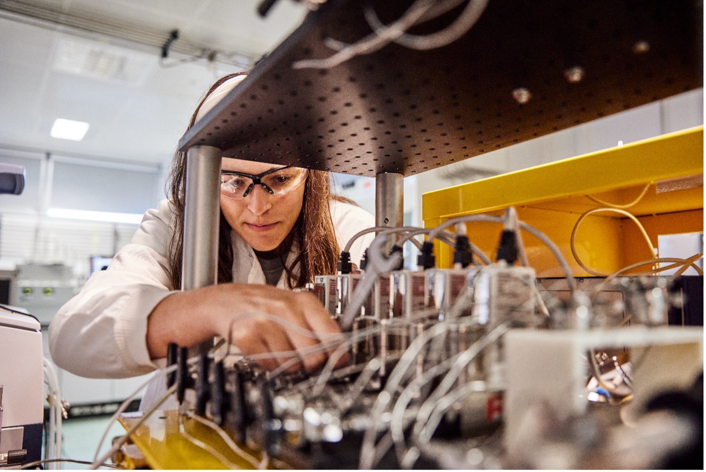 Scientist or technician works on a series of tubes and wires in a lab.
