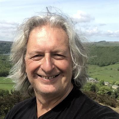 profile shot of Prof Jim Thomas outside with a countryside view behind him