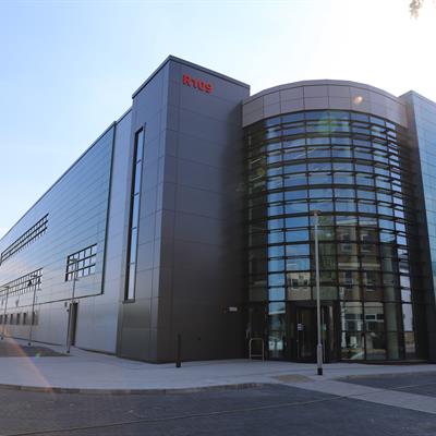 Front of the EPAC building on a sunny day with large windows and a shiny exterior. 