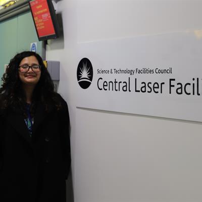 Sneha standing next to a sign that reads "Science and Technology Facilities Council Central Laser Facility".