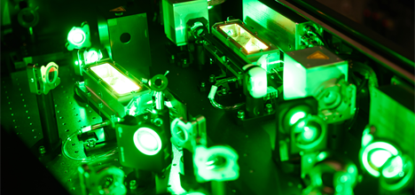 Optical elements on a workbench in Ultra with green glowing light representing the laser light. 