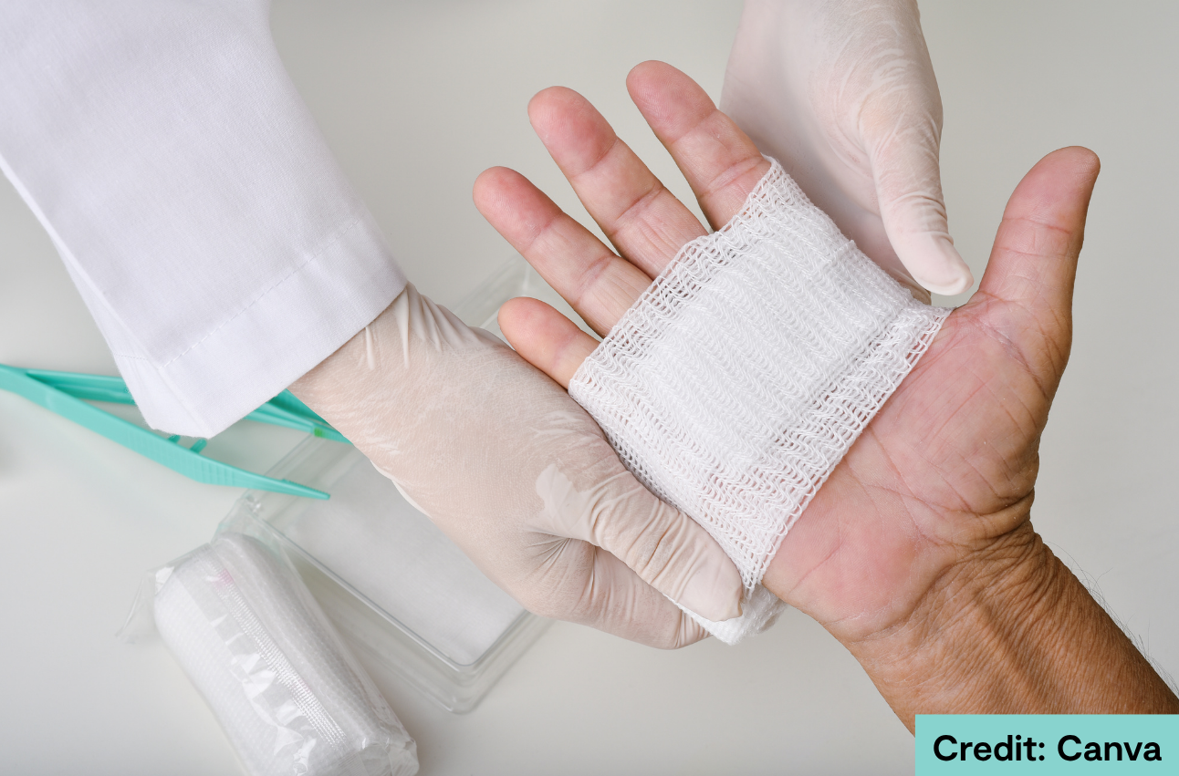 Doctor bandaging a wound on a patient's hand. Credit: Canva