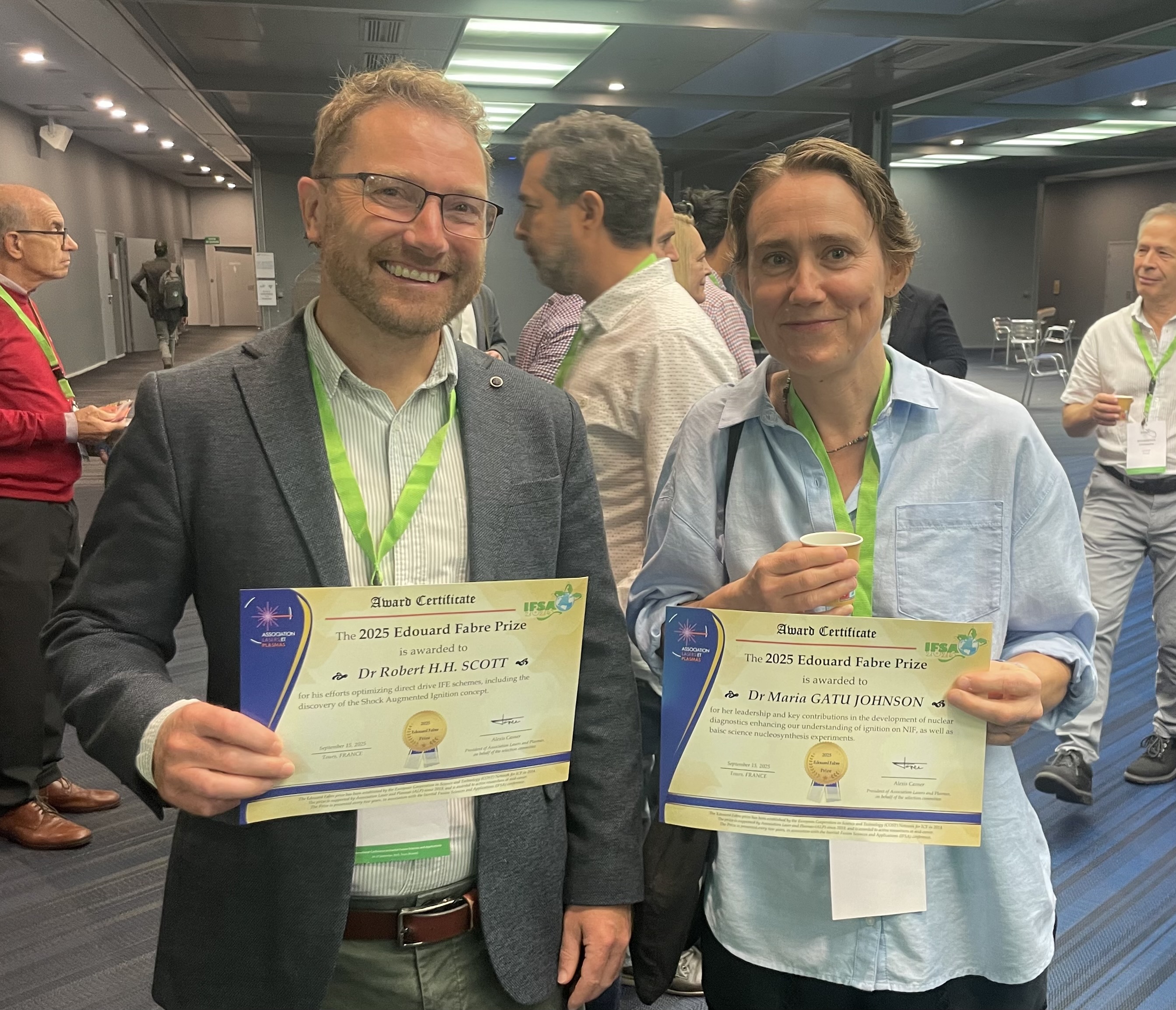 Robbie Scott (left) and the other prize winner Maria Gatu Johnson (right), holding their certificates and smiling at the camera
